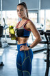 © nazarovsergey - Young woman standing with bottle of water at gym