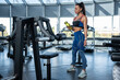 © nazarovsergey - Young woman in sportswear standing with bottle of water at gym