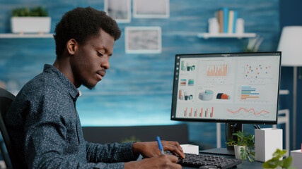 Poster - Selective focus on african american man working from home, taking notes on notepad while remote working on PC from living room. Black guy computer user using business internet online web communication
