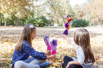 Wall Mural - Two little girl playing with handmade dolls in park