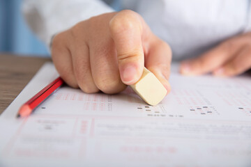 Wall Mural - Close-up shot of examinee holding rubber to modify answer sheet