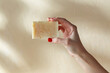 © Syda Productions - natural cosmetics, hygiene and beauty concept - hand holding bar of craft soap on beige background