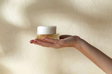 natural cosmetics, hygiene and beauty concept - hand holding bar of craft soap on beige background