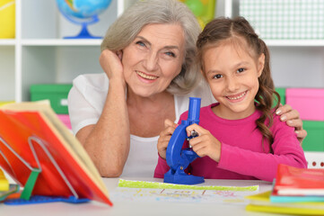 Wall Mural - Girl doing homework with her grandmother at home