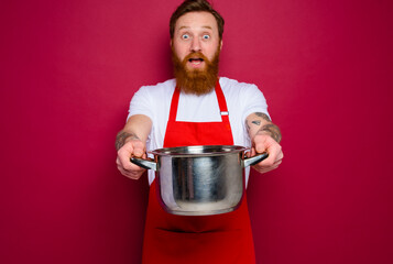 Wall Mural - surprised chef with beard and red apron is ready to cook