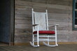 White rocking chair on the porch of an abandoned house.