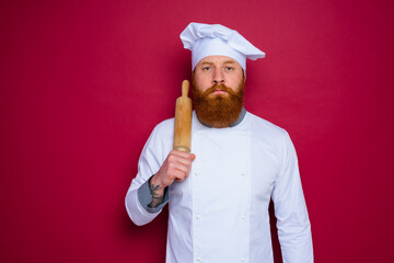 Wall Mural - serious chef with beard and red apron chef holds wooden rolling pin