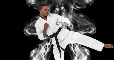 Poster - Composition of male martial artist over trails of smoke on black background