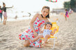 mom and baby sit on the chair beach yellow color in happy time on the beach in evening time with beautiful sunset light and blur tourist background