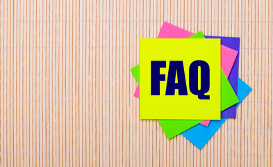 Wall Mural - On a light wooden background, bright multicolored stickers with the text FAQ