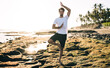 © BullRun - Positive man practicing yoga on seaside in morning