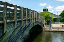 A Bridge Over Water In A Park Leading To A Large Gazebo