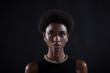 Close up full face portrait of serious african american woman with afro hairstyle on black studio background.