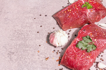 Raw beef steaks on a grey stone background