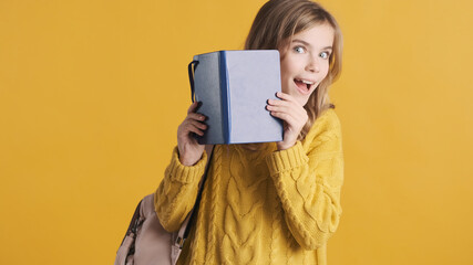 Wall Mural - Positive teenager student girl dressed in sweater peeping from b