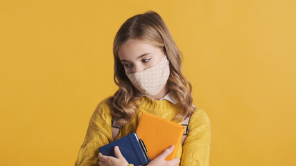 Wall Mural - Upset teenager student girl wearing protective mask feeling sad