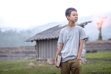 Sticker - Boy standing and holding a bible on the green fields, Focus face, Children's beliefs of christian concept.