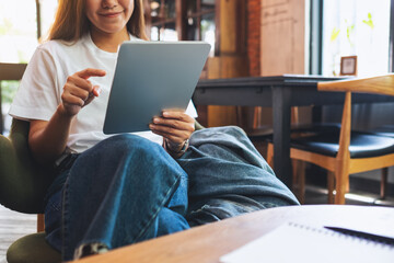 A beautiful young asian woman holding and using digital tablet in cafe