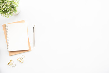 Small blank notebook with pen are on top of white office desk table. Top view with copy space, flat lay.