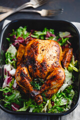 Canvas Print - .Top view of whole roasted chicken with fresh salad in black dish.