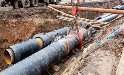 Construction works on large iron pipes at a depth of excavated trench