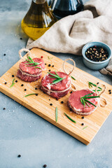 Wall Mural - Raw beef filet mignon steak on a wooden board with rosemary and spices.