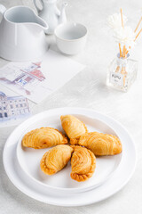 curry puff or kari pap is a snack of Maritime Southeast Asian origin.  It is a small pie consisting of curry with chicken and potatoes in a deep-fried or baked pastry shell. 