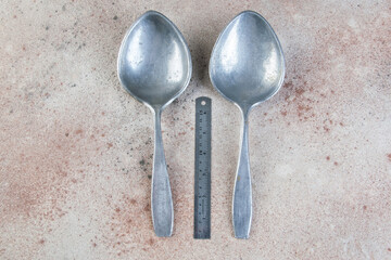 Huge aluminum spoons on concrete background.