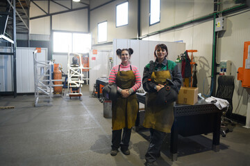 portrait of two welders holding welding masks in their hands and preparing for hard work in a factory