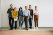 © Jacob Lund - Happy colleagues standing against wall in office