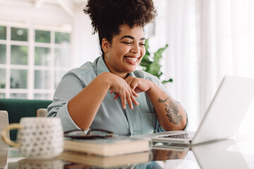 Positive woman video calling using laptop at home