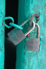 two metal padlocks on a turquoise wooden door