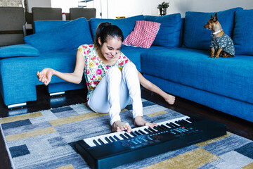 Canvas Print - latin disabled girl with cerebral palsy learning to play the piano with her foot at home in disability concept in Latin America