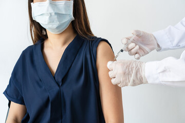 Wall Mural - Asian woman in medical mask getting Covid-19 or flu vaccine at the hospital. Hands of male doctor or professional nurse in medical gloves giving antiviral injection to patient.