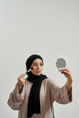 Wall Mural - Young arabian woman in hijab applying cosmetics
