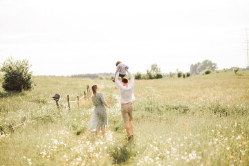 Young happy family having fun in summer day outdoors. Fathe carrying son on shoulders. Copy space.