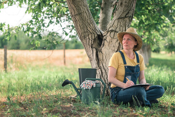 Wall Mural - Female farmer writing notes in walnut orchard