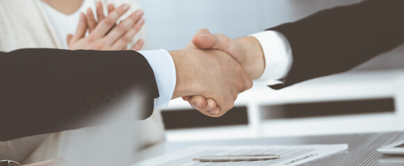 Business people shaking hands after contract signing in modern office. Teamwork and handshake concept