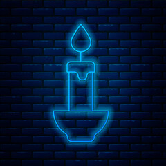 Sticker - Glowing neon line Burning candle icon isolated on brick wall background. Cylindrical candle stick with burning flame. Vector