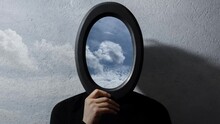 Stop motion photography. Contemporary artwork video collage. Young man holding black frame on face with beautiful time lapse of cloudy sky.