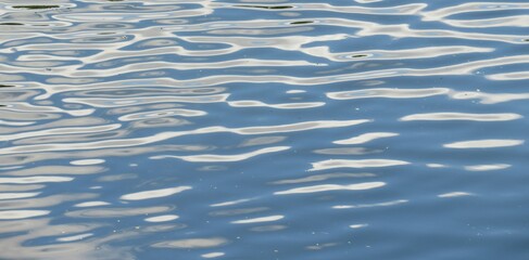 Closeup of light blue river water surface with white spots, natural water background