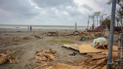 A Muslim Man saying his prayer to Allah while a couple on the beach in a overcast situation at Kuakata in Patuakhali, Bangladesh