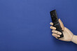 © splitov27 - Wooden hand holding tv remote on blue background