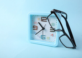 Wall Mural - Alarm clock with glasses on blue background