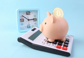 Wall Mural - Piggy bank with bitcoin, calculator and clock on a blue background