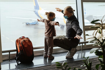 man with girl ready to fly by airplane and the airport. father and child looking though the lounge w