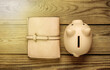 Piggy bank with leather wallet on wooden background. Top view