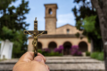 Man's Hand Holding A Crucifix In Front Of A Church