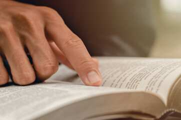 young man pointing to a bible topic and read the Bible on Sundays to receive the blessings of God.