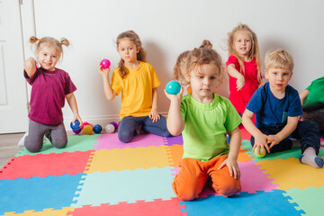 Wall Mural - Lovely toddler boy playing with small balls and plastic basket